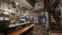 Saat masuk, kamu akan melihat nuansa jadul dengan paduan warna-warna keramik nyentrik di lantainya, serta ragam lukisan yang memenuhi dinding. Interior kayu dengan lampu keorenan menambah vibes hangat dari kafe ini
