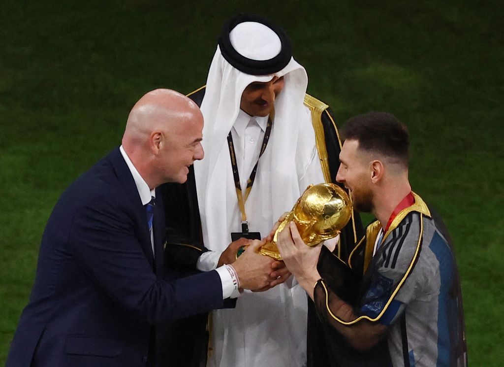 Soccer Football - FIFA World Cup Qatar 2022 - Final - Argentina v France - Lusail Stadium, Lusail, Qatar - December 18, 2022 FIFA president Gianni Infantino hands the World Cup trophy to Argentina's Lionel Messi as Emir of Qatar Sheikh Tamim bin Hamad Al Thani watches REUTERS/Paul Childs
