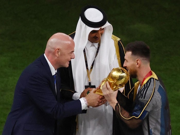 Soccer Football - FIFA World Cup Qatar 2022 - Final - Argentina v France - Lusail Stadium, Lusail, Qatar - December 18, 2022 FIFA president Gianni Infantino hands the World Cup trophy to Argentina's Lionel Messi as Emir of Qatar Sheikh Tamim bin Hamad Al Thani watches REUTERS/Paul Childs