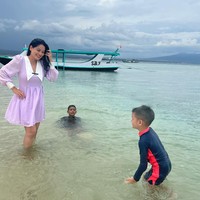Berlibur bersama kedua putranya, Titi juga terlihat mengawasi dan menemani kedua anaknya itu saat bermain di pantai. Dengan rambut panjang yang dibiarkan terurai dan pulasan makeup natural, Titi tampil cantik mengenakan dress lengan panjang berwarna ungu. Foto: Instagram/@titi_kamall