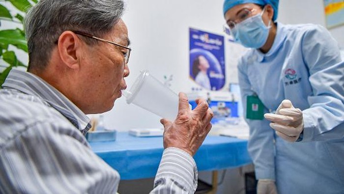 A health worker (R) receives a dose of inhalable Covid-19 coronavirus vaccine at a health service center in Chaoyang district in Beijing on November 22, 2022. - China OUT (Photo by CNS / AFP) / China OUT (Photo by -/CNS/AFP via Getty Images)