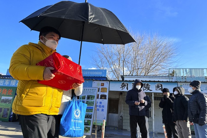 Family members in protective gear collect the cremated remains of their loved one bundled with yellow cloth at a crematorium in Beijing, Saturday, Dec. 17, 2022. Deaths linked to the coronavirus are appearing in Beijing after weeks of China reporting no fatalities, even as the country is seeing a surge of cases. (AP Photo/Ng Han Guan)