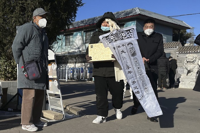 Family members in protective gear collect the cremated remains of their loved one bundled with yellow cloth at a crematorium in Beijing, Saturday, Dec. 17, 2022. Deaths linked to the coronavirus are appearing in Beijing after weeks of China reporting no fatalities, even as the country is seeing a surge of cases. (AP Photo/Ng Han Guan)
