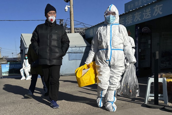 Family members in protective gear collect the cremated remains of their loved one bundled with yellow cloth at a crematorium in Beijing, Saturday, Dec. 17, 2022. Deaths linked to the coronavirus are appearing in Beijing after weeks of China reporting no fatalities, even as the country is seeing a surge of cases. (AP Photo/Ng Han Guan)