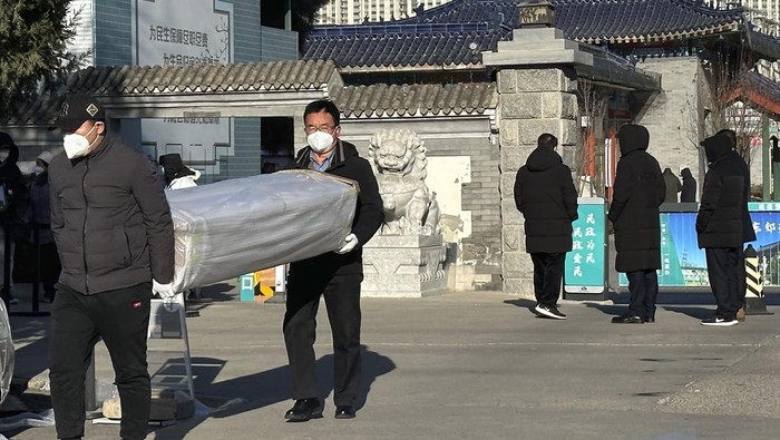 Virus Outbreak China Family members in protective gear collect the cremated remains of their loved one bundled with yellow cloth at a crematorium in Beijing, Saturday, Dec. 17, 2022. Deaths linked to the coronavirus are appearing in Beijing after weeks of China reporting no fatalities, even as the country is seeing a surge of cases. (AP Photo/Ng Han Guan)