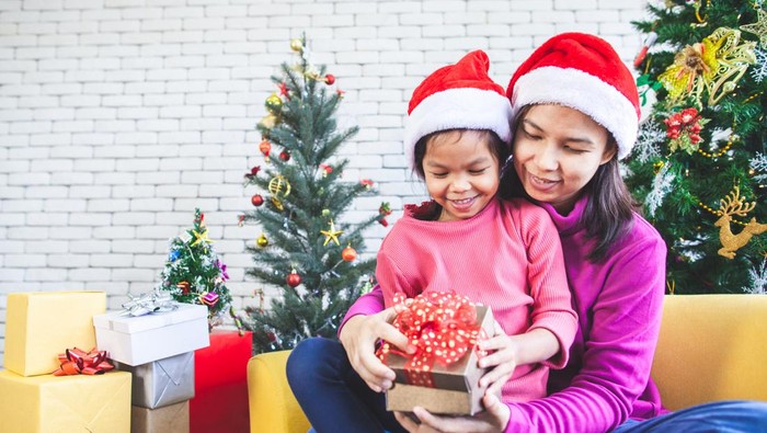 Cute asian child girl with her mother holding beautiful gift box and surprise with gift in Christmas celebration