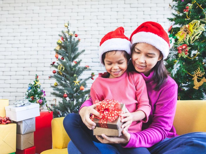 Cute asian child girl with her mother holding beautiful gift box and surprise with gift in Christmas celebration