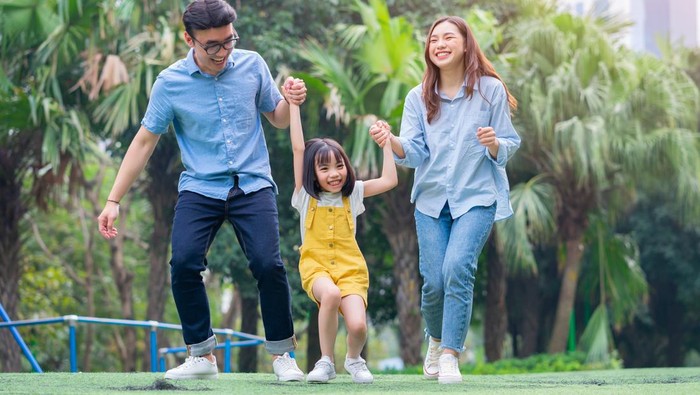 Image of young Asian family playing together at park