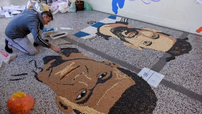 TOPSHOT - Kosovar artist Alkent Pozhegu works on the last details of his mosaic, made with grain and seeds on the ground, depicting Argentina's forward Lionel Messi (L) and France's forward Kylian Mbappe in the town of Gjakova on December 17, 2022, on the eve of the Qatar 2022 World Cup final match between Argentina and France. - RESTRICTED TO EDITORIAL USE - MANDATORY MENTION OF THE ARTIST UPON PUBLICATION - TO ILLUSTRATE THE EVENT AS SPECIFIED IN THE CAPTION (Photo by Armend NIMANI / AFP) / RESTRICTED TO EDITORIAL USE - MANDATORY MENTION OF THE ARTIST UPON PUBLICATION - TO ILLUSTRATE THE EVENT AS SPECIFIED IN THE CAPTION / RESTRICTED TO EDITORIAL USE - MANDATORY MENTION OF THE ARTIST UPON PUBLICATION - TO ILLUSTRATE THE EVENT AS SPECIFIED IN THE CAPTION (Photo by ARMEND NIMANI/AFP via Getty Images)