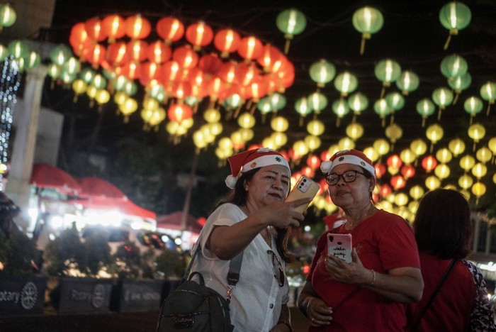 Warga berfoto dengan latar belakang lampion dekorasi bertema Natal di Balai Kota, Solo, Jawa Tengah, Selasa (20/12/2022). Pemasangan lampion tersebut untuk memeriahkan perayaan Natal dan Tahun Baru di Kota Solo. ANTARA FOTO/Mohammad Ayudha/aww.