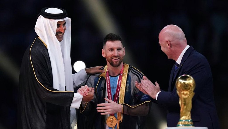 Emir of Qatar, Sheikh Tamim bin Hamad Al Thani dresses Argentinas Lionel Messi with traditional Arab bisht ahead of the Trophy presentation as FIFA President Gianni Infantino looks on following the FIFA World Cup final at Lusail Stadium, Qatar. Picture date: Sunday December 18, 2022. (Photo by Mike Egerton/PA Images via Getty Images)
