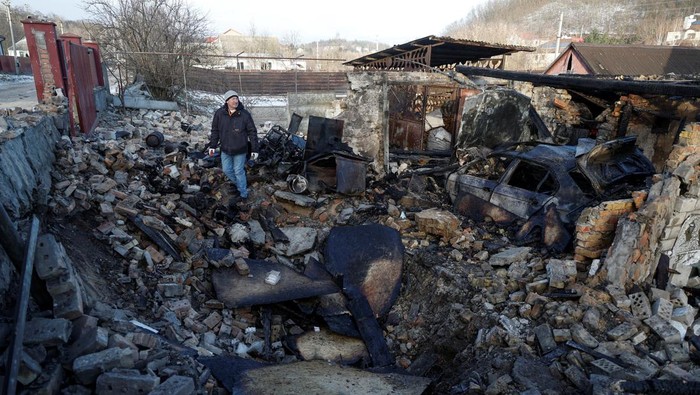 Local resident Mykola Kobzarenko looks at investigators as they work at the site of his house damaged during a Russian drone strike, amid Russia's attack on Ukraine, in the village of Stari Bezradychi, in Kyiv region, Ukraine December 19, 2022. REUTERS/Valentyn Ogirenko