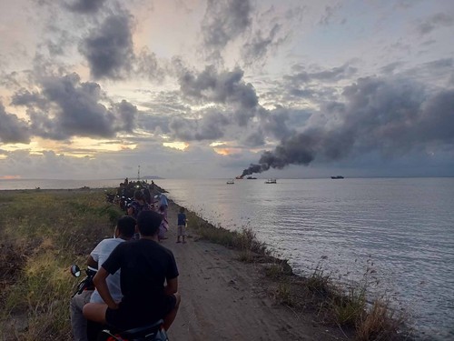 Warga setempat saat menyaksikan terbakarnya tiga Kapal Motor (KM) tangkap ikan di laut Desa Pengambengan, Kecamatan Negara, Kabupaten Jembrana, Selasa (20/12/2022). (I Putu Adi Budiastrawan )