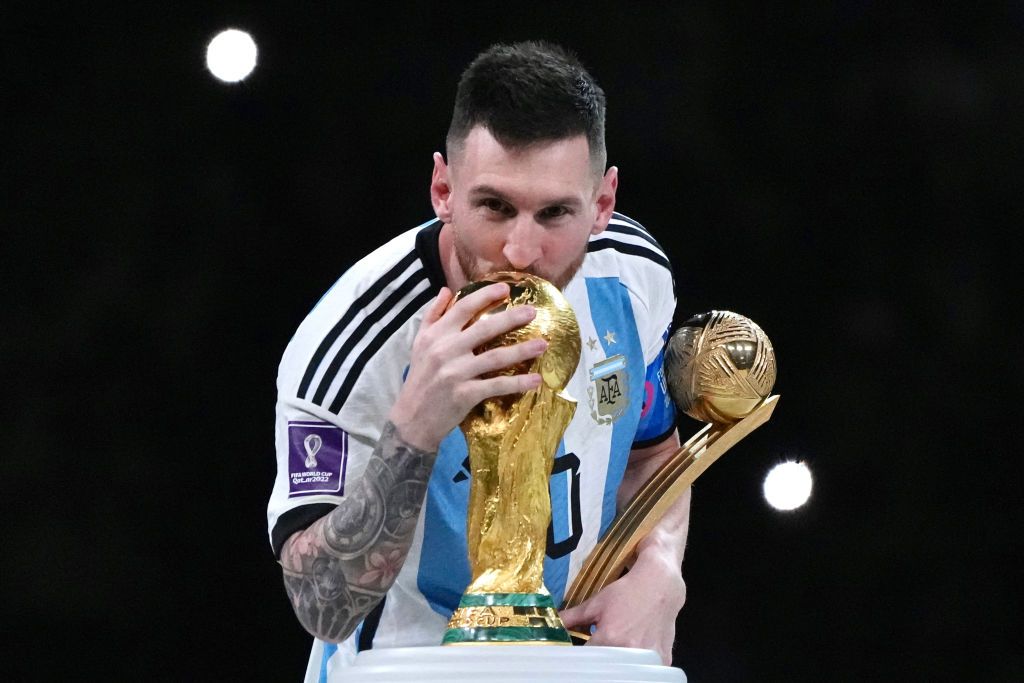 LUSAIL CITY, QATAR - DECEMBER 18: Adidas Golden Ball winner Lionel Messi of Argentina kisses the FIFA World Cup Winner's Trophy at the award ceremony following the FIFA World Cup Qatar 2022 Final match between Argentina and France at Lusail Stadium on December 18, 2022 in Lusail City, Qatar. (Photo by Cui Nan/China News Service/VCG via Getty Images)
