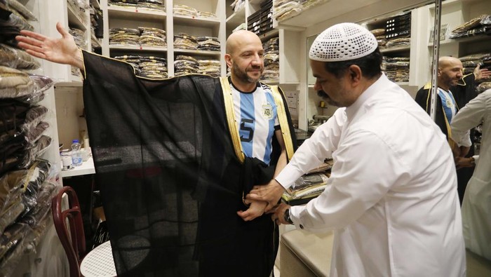 DOHA, QATAR - DECEMBER 21: A man tries on a cloak, Bisht, at Souq Waqif Bazaar in Doha, Qatar on December 21, 2022. The traditional Arab world cloak named 