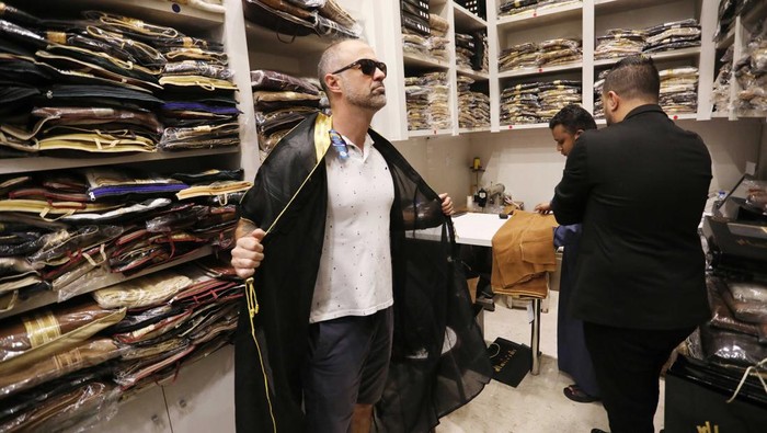 DOHA, QATAR - DECEMBER 21: A man tries on a cloak, Bisht, at Souq Waqif Bazaar in Doha, Qatar on December 21, 2022. The traditional Arab world cloak named 