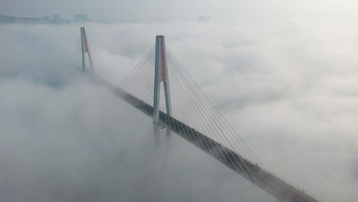 Ketutup Kabut, Jembatan Ini Kaya Dibangun di Atas Awan CHONGQING, CHINA - DECEMBER 21: Aerial view of a bridge shrouded in thick fog on December 21, 2022 in Chongqing, China. (Photo by He Penglei/China News Service/VCG via Getty Images)