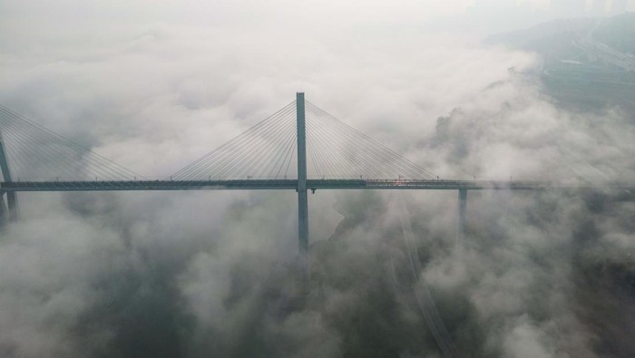 Ketutup Kabut, Jembatan Ini Kaya Dibangun di Atas Awan CHONGQING, CHINA - DECEMBER 21: Aerial view of a bridge shrouded in thick fog on December 21, 2022 in Chongqing, China. (Photo by He Penglei/China News Service/VCG via Getty Images)