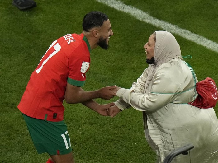 Morocco's Sofiane Boufal celebrates with a mother on the pitch after his team's win in the World Cup quarterfinal soccer match between Morocco and Portugal, at Al Thumama Stadium in Doha, Qatar, Saturday, Dec. 10, 2022. (AP Photo/Alessandra Tarantino)