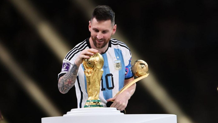 LUSAIL CITY, QATAR - DECEMBER 18: Lionel Messi of Argentina admires the FIFA World Cup Trophy at the awards ceremony during the FIFA World Cup Qatar 2022 Final match between Argentina and France at Lusail Stadium on December 18, 2022 in Lusail City, Qatar. (Photo by Matthew Ashton - AMA/Getty Images)