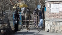 Seorang mahasiswi Afghanistan berdiri di depan gerbang masuk yang dijaga pasukan Taliban di Universitas Kabul di Kabul, Afghanistan, Rabu (21/12/2022).  