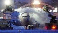 Kru maskapai sedang membersihkan salju yang menyelimuti badan pesawat American Airlines di Bandara Internasional Paul, Amerika Serikat, Kamis (22/12/2022). David Joles/Star Tribune/AP.