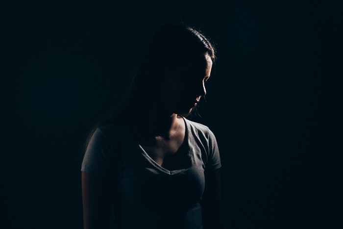 Sad woman in dark room. Depression and anxiety disorder concept