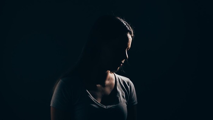 Sad woman in dark room. Depression and anxiety disorder concept