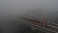 Kereta Metro Jalur Oranye (OLMT) melaju di tengah cuaca berkabut.   