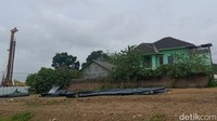 Di dekat rumah itu ada alat berat penanam tiang pancang dan truk molen proyek tol. Di belakangnya ada gundukan tanah uruk yang setara dengan setengah ketinggian rumah itu. Foto: Achmad Hussein Syauqi/detikJateng 