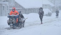 Warga melintasi di jalan yang tertutup oleh salju di Weihai, China, Jumat (23/12/2022).