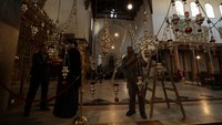 Seorang pekerja pemeliharaan membersihkan perlengkapan penerangan di Gereja Kelahiran Yesus di kota Bethlehem.   