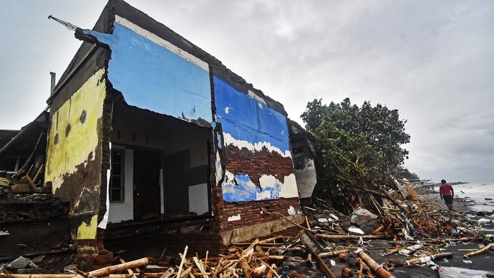 Sejumlah warga melintas di dekat bangunan rumah yang roboh di Lingkungan Mapak Indah, Kelurahan Jempong Baru, Mataram, NTB, Sabtu (24/12/2022). Gelombang tinggi yang disertai angin kencang yang terjadi sejak Jumat (23/12) di daerah tersebut mengakibatkan belasan rumah warga yang berada di pesisir pantai rusak dan roboh tergerus abrasi. ANTARA FOTO/Ahmad Subaidi/YU