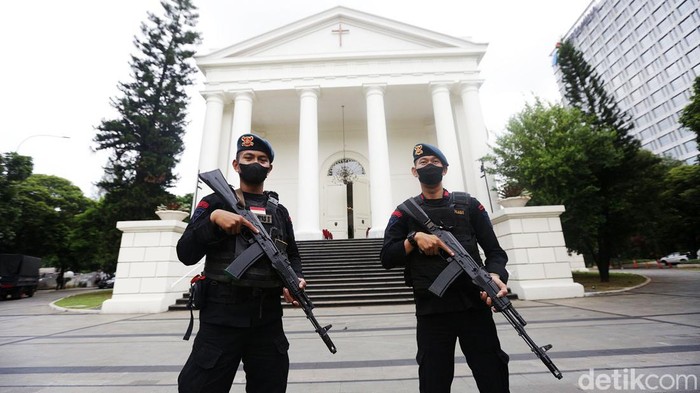 Petugas Brimob Kepolisian berjaga dengan menggunakan senjata laras panjang di Gereja GPIB Immanuel Jakarta Pusat, Sabtu (24/12/2022). Hal ini guna mengantisipasi hal hal yang tidak diinginkan dan memberikan rasa aman dan nyaman para umat Kristiani yang akan melakukan misa malam Natal. Selain petugas TNI dan Polri juga tampak anggota Banser ikut menjaga keamanan gereja GPIB Immanuel