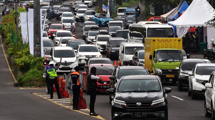 Sejumlah anggota Satlantas Polres Bogor bersama Dishub Kabupaten Bogor mengatur arus lalu lintas kendaraan yang memasuki Simpang Gadog, Ciawi saat diberlakukannya sistem satu arah menuju jalur wisata Puncak, Kabupaten Bogor, Jawa Barat, Sabtu (24/12/2022). Polres Bogor mencatat sebanyak 57 ribu kendaraan memasuki jalur wisata Puncak, Kabupaten Bogor menjelang Hari Raya Natal dam Tahun Baru 2023 terhitung mulai Jumat (23/12/2022) pukul 00.00 WIB hingga Sabtu (24/12/2022) pukul 12.30 WIB. ANTARA FOTO/Arif Firmansyah/YU