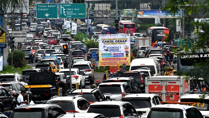 Sejumlah anggota Satlantas Polres Bogor bersama Dishub Kabupaten Bogor mengatur arus lalu lintas kendaraan yang memasuki Simpang Gadog, Ciawi saat diberlakukannya sistem satu arah menuju jalur wisata Puncak, Kabupaten Bogor, Jawa Barat, Sabtu (24/12/2022). Polres Bogor mencatat sebanyak 57 ribu kendaraan memasuki jalur wisata Puncak, Kabupaten Bogor menjelang Hari Raya Natal dam Tahun Baru 2023 terhitung mulai Jumat (23/12/2022) pukul 00.00 WIB hingga Sabtu (24/12/2022) pukul 12.30 WIB. ANTARA FOTO/Arif Firmansyah/YU
