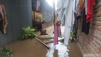 Seorang warga tampak berada di tengah genangan banjir air sambil menggendong bayinya. (Foto: Edward Ridwan/detikSulsel)