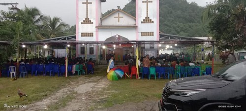 Umat kristiani menerobos hujan memasuki gereja Katolik di Merombok, Labuan Bajo. (IST)
