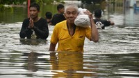 Warga mengevakuasi barang-barangnya dari genangan banjir.
