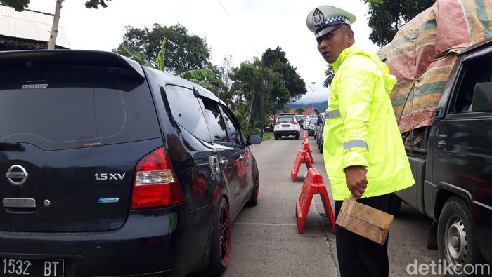 Polisi membawa balok kayu untuk mengganjal kendaraan yang tidak kuat menanjak di jalur Cepogo Boyolali, Minggu (25/12/2022).