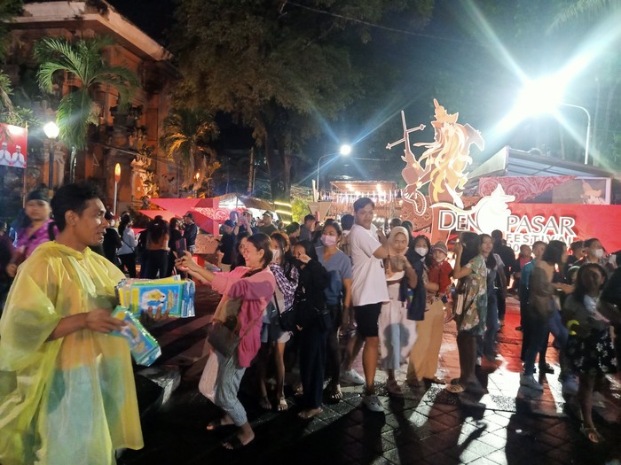 Salah satu penjual jas hujan di Denpasar Festival ke-15, yakni Bambang Purwanto ketika tengah menawarkan jas hujan kepada pengunjung, Minggu (25/12/2022) di kawasan Patung Catur Muka Denpasar, Bali. (Ni Made Lastri Karsiani Putri-detikBali)