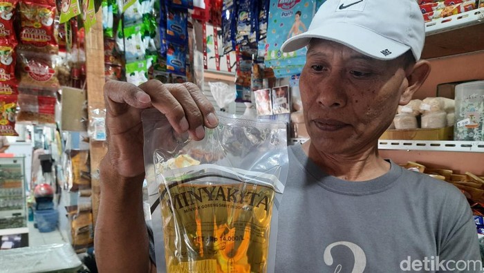 Seorang pedagang di Pasar Pucang Surabaya menunjukkan stok Minyakita yang dia punya