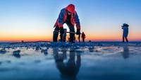 Seorang warga terlihat mengebor lapisan es di Danau Chagan, Songyuan, Provinsi Jilin, China, Senin (26/12/2022).