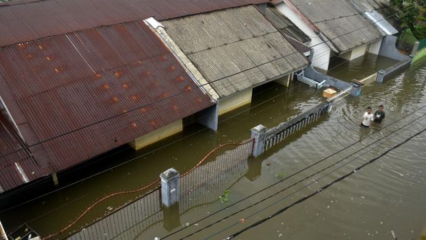 Warga berusaha menyeberangi jalan yang tergenang banjir di Kecamatan Manggala, Makassar, Sulawesi Selatan, Minggu (25/12/2022). Curah hujan yang tinggi dalam beberapa hari membuat sungai dan waduk di kota Makassar meluap sehingga mengakibatkan ratusan rumah dan jalan terendam banjir. ANTARA FOTO/Abriawan Abhe/nym.