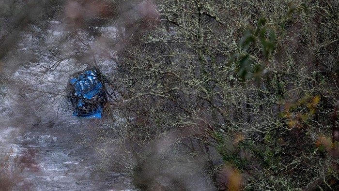 Bus Jatuh ke Sungai Saat Cuaca Buruk di Spanyol, 6 Orang Tewas The wreck of a bus lies in the Lerez river after it plunged while crossing a bridge, killing four people, in Cerdedo-Cotobade, northwestern Spain, on December 25, 2022. - The accident occurred on December 24 night near Vigo and the border with Portugal. The regional La Voz de Galicia newspaper said the bus was carrying people visiting their loved ones jailed in Monterroso in central Galicia. Rescue operations had to be suspended overnight due to bad weather but resumed in the morning. (Photo by Brais Lorenzo / AFP) (Photo by BRAIS LORENZO/AFP via Getty Images)
