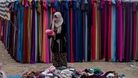 Wanita penjual pakaian bekas menunggu pembeli di pinggir jalan. Foto: AFP via Getty Images/DELIL SOULEIMAN