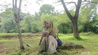 Salah seorang warga terlihat khusyuk membaca ayat suci Alquran saat ziarah di makam massal korban tsunami. (Agus Setyadi/detikSumut)