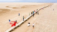 Gelombang panas juga terjadi di China, dan menyebabkan Danau Poyang mengering. Tampak warga berjalan di jembatan kuno yang muncul dari Danau Poyang yang kering di Jiujiang, Provinsi Jiangxi, China, pada Rabu, (21/9/2022). Li Jie/VCG via Getty Images.