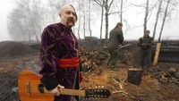 Seorang seniman berpakaian Cossack memegang gitarnya setelah penampilan tentara Garda Nasional Ukraina untuk menandai Natal.  