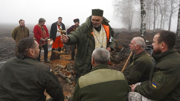 Momen Natal di Garis Perang, Seniman Hibur Tentara Ukraina A chaplain blesses Ukraine's National Guard soldiers to mark Christmas at their positions close to the Russian border near Kharkiv, Ukraine, Saturday, Dec. 24 2022. (AP Photo/Andrii Marienko)